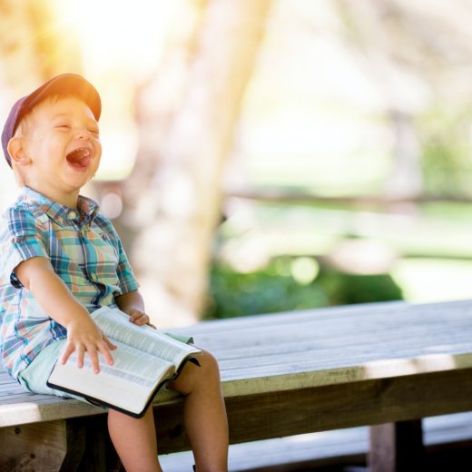 Child reading book, laughing